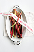 Rhubarb stems and ribbon with writing in a casserole dish