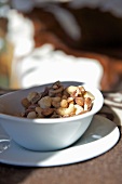 A selection of nuts in a white porcelain bowl on a plate