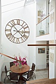 View of dining area beneath antique wall clock in glass-roofed anteroom