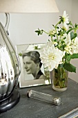 White flowers in glass vase next to framed photograph