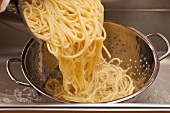 Spaghetti being poured into a colander
