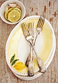 Ovale Teller, Gabel und Schälchen mit Zitrone und Knoblauch