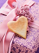 A gift box decorated with a bow, roses and a heart-shaped biscuit