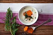 Cream of potato soup garnished with carrots and carrot leaves