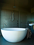 Frei stehende weiße Designer- Badewanne, die einer halben Eierschale gleicht in einem maskulin wirkenden Badezimmer