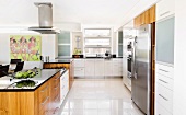 Kitchen units in white and wood and over-size stainless steel refrigerator in a wide, open kitchen