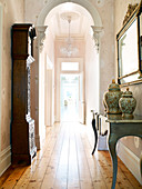 Long hallway with simple wooden flooring, arch and antique furniture