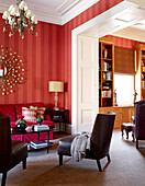 Traditional living room in warm shades of red with deep pink couch and adjoining library