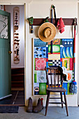 Straw hat and gardening utensils hanging on coat rack in rustic foyer