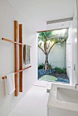White designer bathroom with separate shower area in front of glass wall with view of garden