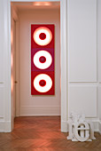 Wood-panelled doorway leading to hall with view of red 70s light sculpture
