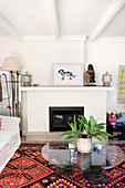 Round glass table on brightly patterned rug in front of living room fireplace