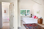 View into simple bedroom with colourful rug