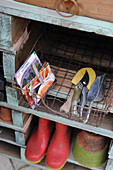 Gardening tools and shoes on wooden shelving