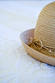 Partially visible ladies straw hat on a white quilt