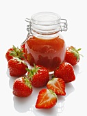 A jar of strawberry jam and fresh strawberries