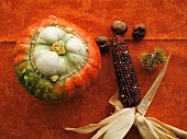A pumpkin, a corn cob and chestnuts