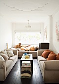 Bright living room with three sand-coloured sofas and colour-coordinated scatter cushions