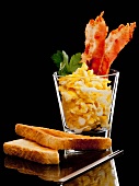 Scrambled egg with bacon in a glass with toast