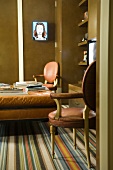 Leather-covered ottoman and chairs, striped carpet and fitted cupboards in living room