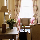 Table lamp on table next to lounge area - elegant armchairs and coffee table in front of window with gathered curtains