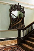 Traditionelles Treppenhaus - Spiegel mit aufwendig geschnitztem Holzrahmen und Stuckarbeiten an Wand und Teppichläufer mit orientalischem Muster
