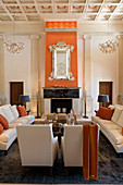 Grand salon with coffered ceiling and pale, classic upholstered seating in front of open fireplace