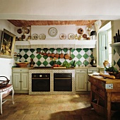 Traditional, French-style country house kitchen with stone floor and chequered wall tiles