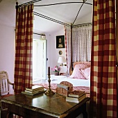 French canopy bed with red and white gingham and spotted curtains