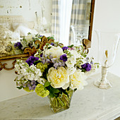 Bouquet on marble shelf in front of mirror with dull spots