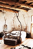 Bed hand crafted from twisted branches in rustic bedroom with wood-beamed ceiling