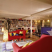 Red sofas and full bookcase in festively decorated loft apartment with corrugated sheet metal ceiling