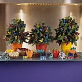 Small Christmas tree arrangements with brightly wrapped sweeties and colourful fir cones