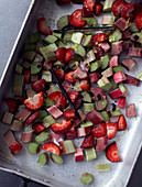 Rhubarb and strawberry pieces with vanilla sugar and pods on a baking tray