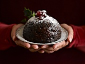 Hands holding a Christmas pudding