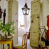 Vintage-style room with open folding doors and view of lantern-shaped pendant lamp and table in background