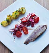 A herring fillet, tomato salad and potatoes (Scandinavia)