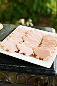 Shortbread Pig Cookies with Pink Icing on a White Platter; Outdoor Table