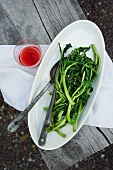 Sauteed Rapini in a White Bowl Drizzled with Balsamic Vinegar and Olive Oil; Glass of Rose Wine