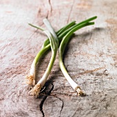 Three spring onions on a wooden surface