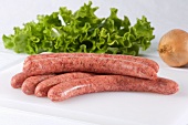 Raw pork sausages, mixed leaf salad and an onion