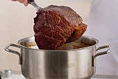 Roasting beef being removed from a pot