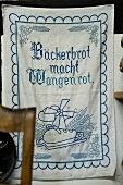 A tea towel with a proverb hanging on a wall