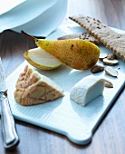 Various types of cheese, pears and crackers on a porcelain board