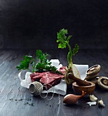 An arrangement of beef, celery, mushrooms, kitchen twine and a mortar