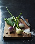 Spring onions, garlic, salt and pepper on a wooden board