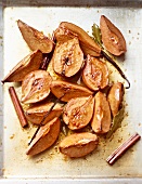 Quinces on a baking tray with vanilla, cinnamon and bay leaves