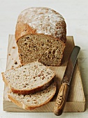 Organic country bread on a chopping board (sliced)