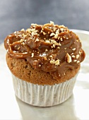 A cupcake topped with caramel and chopped nuts