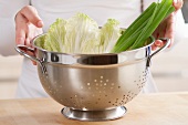 Spring onions and lettuce leaves in a colander